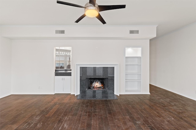 unfurnished living room with ceiling fan, dark wood-type flooring, built in features, and crown molding