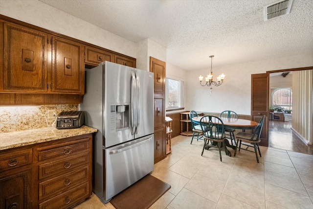 kitchen with a healthy amount of sunlight, brown cabinetry, visible vents, and stainless steel refrigerator with ice dispenser