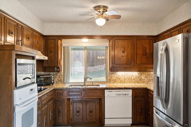 kitchen with a toaster, appliances with stainless steel finishes, a sink, under cabinet range hood, and backsplash