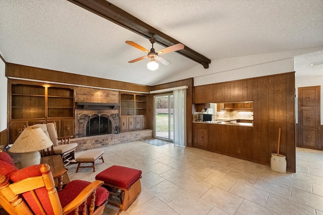 living area with a textured ceiling, vaulted ceiling with beams, a fireplace, a ceiling fan, and built in features