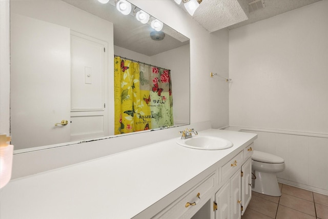 bathroom with a wainscoted wall, visible vents, toilet, vanity, and tile patterned floors