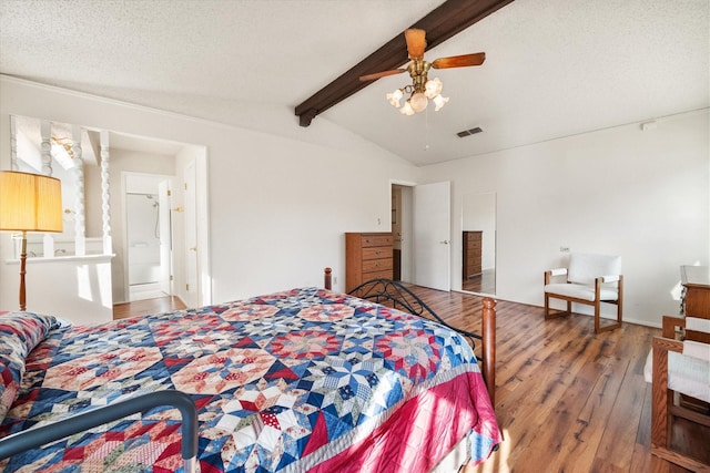 bedroom featuring vaulted ceiling with beams, visible vents, a ceiling fan, a textured ceiling, and hardwood / wood-style flooring