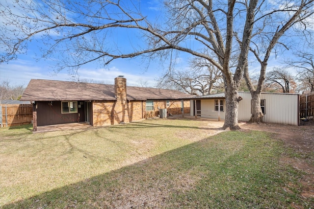 rear view of property with a lawn, a chimney, fence, and central AC