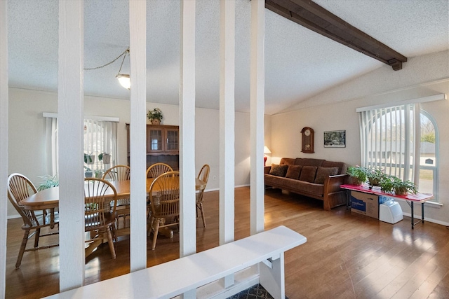 dining area featuring vaulted ceiling with beams, a textured ceiling, baseboards, and wood finished floors