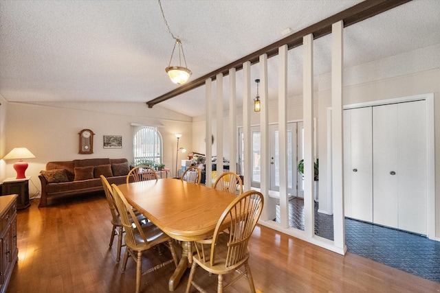 dining area with lofted ceiling with beams, a textured ceiling, and wood finished floors