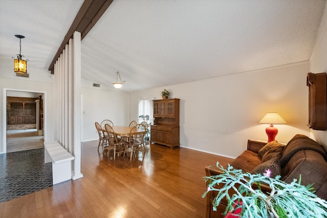 dining room featuring vaulted ceiling with beams, a fireplace, wood finished floors, visible vents, and baseboards