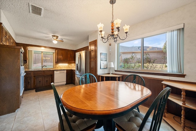 dining area featuring ceiling fan with notable chandelier, visible vents, a textured ceiling, and light tile patterned flooring