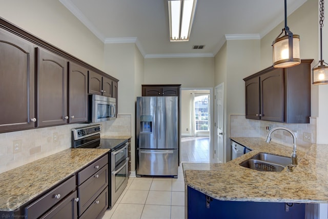 kitchen featuring appliances with stainless steel finishes, decorative backsplash, dark brown cabinets, pendant lighting, and sink