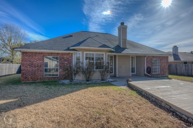 rear view of house with a wooden deck and a lawn