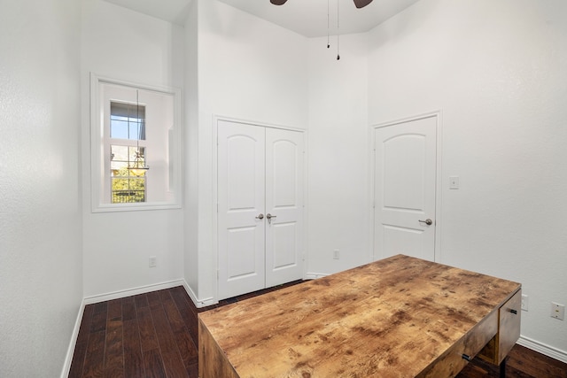 office area featuring ceiling fan, baseboards, a high ceiling, and dark wood-style floors