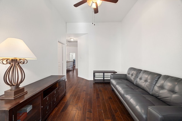 living area with baseboards, dark wood-type flooring, and ceiling fan