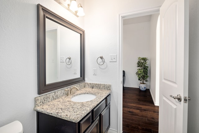 bathroom featuring vanity, toilet, wood finished floors, and baseboards