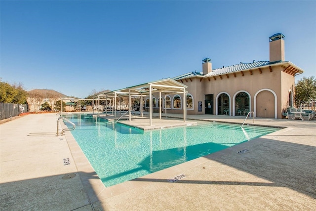 community pool with a patio area and fence