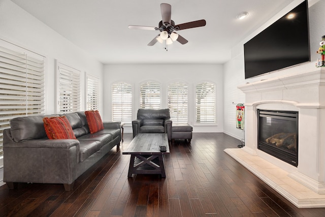 living area featuring a fireplace, baseboards, a ceiling fan, and wood-type flooring