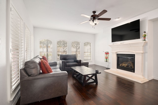 living area with ceiling fan, baseboards, a glass covered fireplace, and hardwood / wood-style flooring