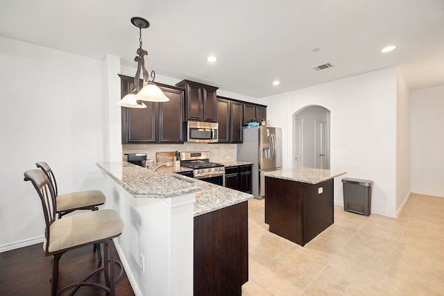 kitchen with visible vents, tasteful backsplash, a kitchen island, arched walkways, and appliances with stainless steel finishes