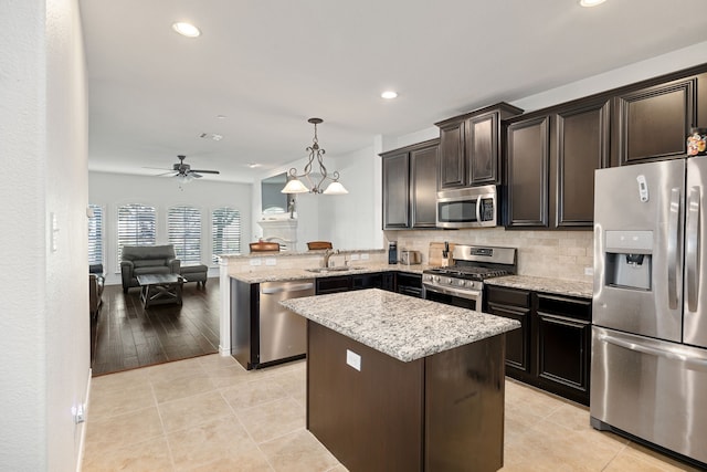 kitchen with a sink, light stone counters, a kitchen island, tasteful backsplash, and appliances with stainless steel finishes