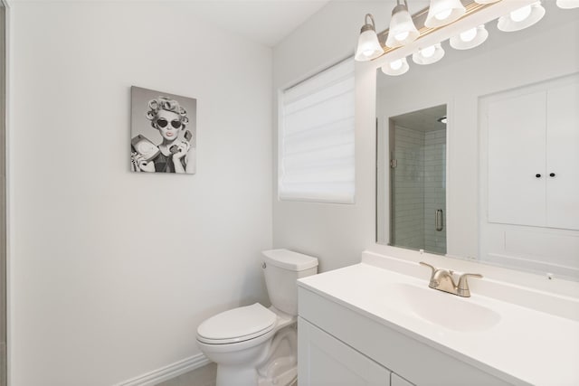 bathroom featuring toilet, vanity, and a shower with shower door