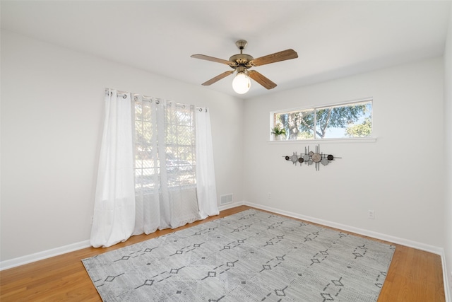 empty room featuring ceiling fan, light wood-type flooring, and a wealth of natural light