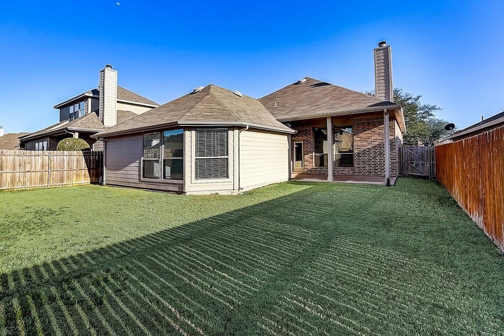 back of house with a patio area and a yard