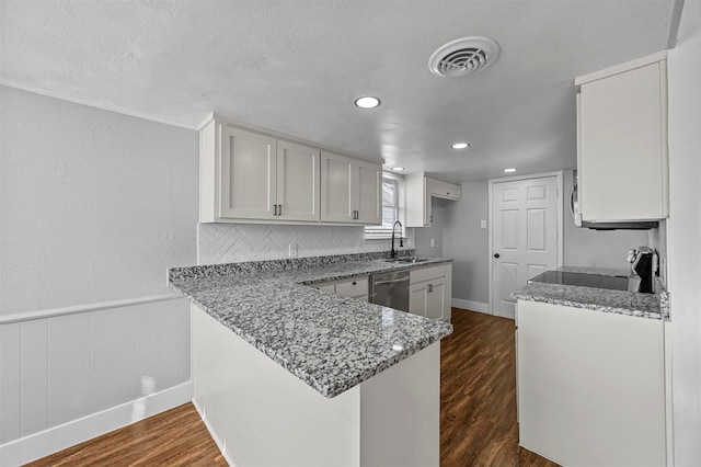 kitchen with stainless steel dishwasher, kitchen peninsula, dark hardwood / wood-style floors, and white cabinetry