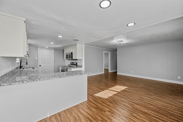 kitchen featuring kitchen peninsula, sink, white cabinetry, light stone countertops, and stainless steel appliances