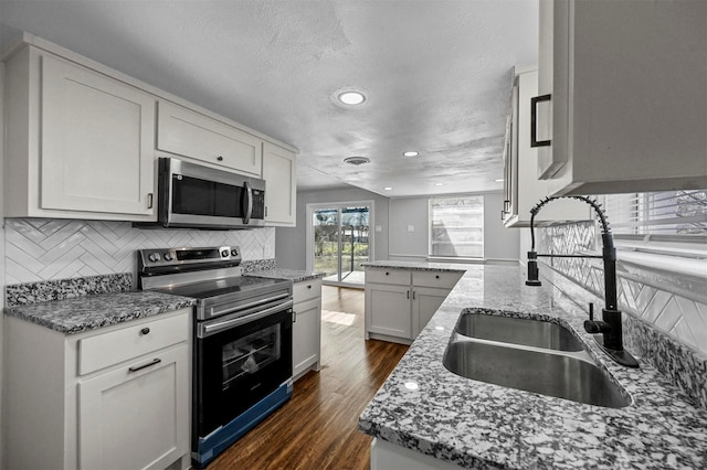 kitchen featuring light stone countertops, white cabinets, appliances with stainless steel finishes, and sink