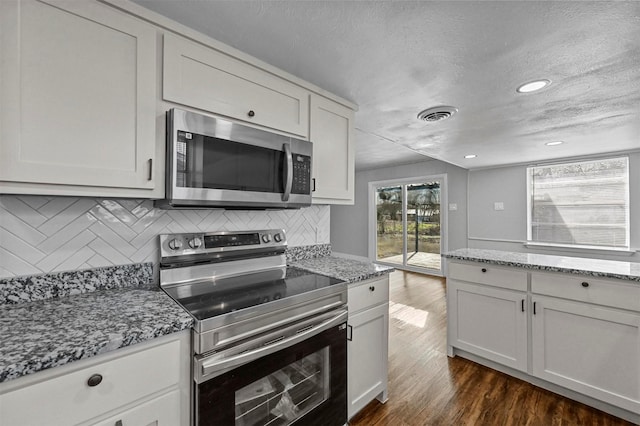 kitchen featuring backsplash, light stone countertops, stainless steel appliances, a textured ceiling, and white cabinets