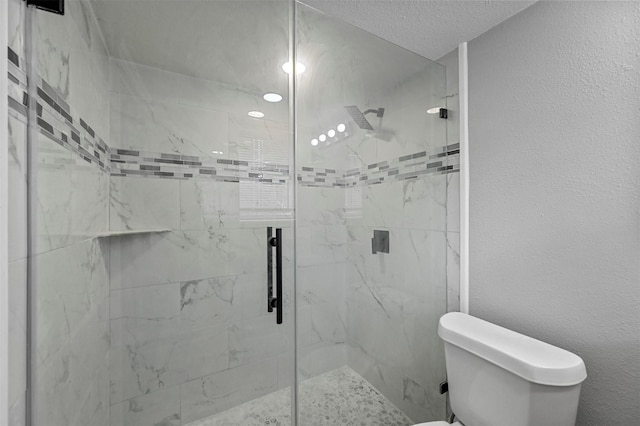 bathroom with a textured ceiling, toilet, and walk in shower