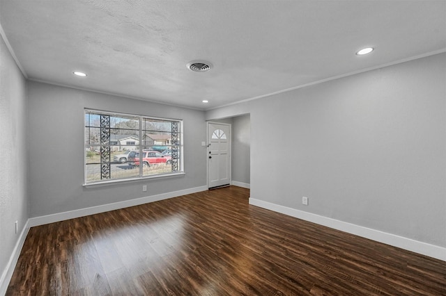 spare room featuring dark hardwood / wood-style floors, ornamental molding, and a textured ceiling