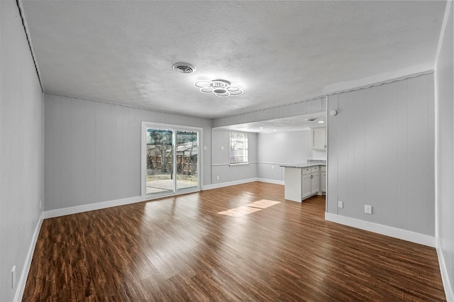 unfurnished living room with wood walls, hardwood / wood-style floors, and a textured ceiling