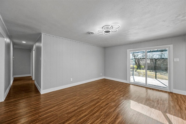 empty room featuring a textured ceiling and dark hardwood / wood-style floors