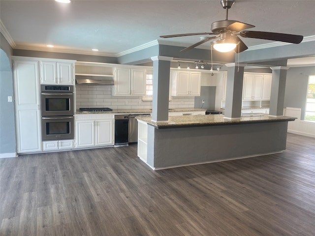 kitchen with stainless steel appliances, backsplash, a kitchen island, white cabinets, and light stone counters