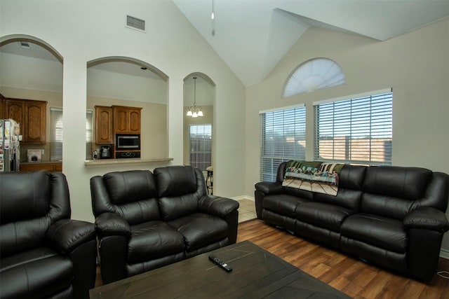 living room with high vaulted ceiling, a chandelier, and hardwood / wood-style floors