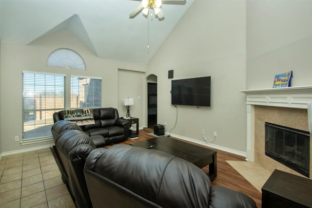 living room with ceiling fan, a high end fireplace, tile patterned floors, and high vaulted ceiling