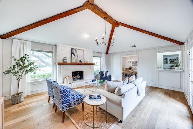 living room with plenty of natural light, light wood-type flooring, a fireplace, and a chandelier