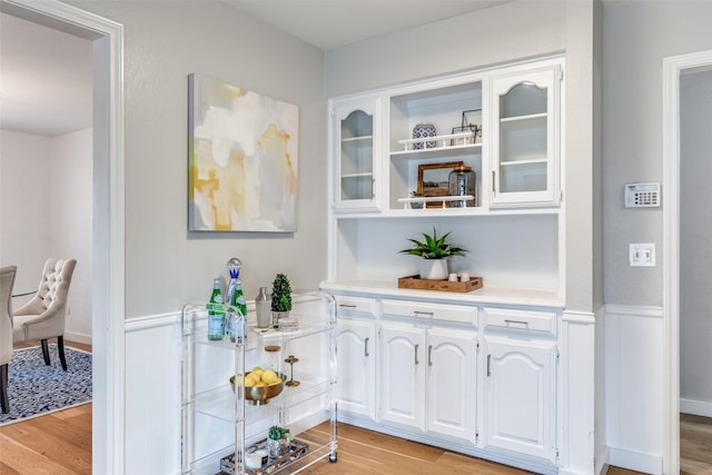 bar with white cabinetry and light hardwood / wood-style flooring