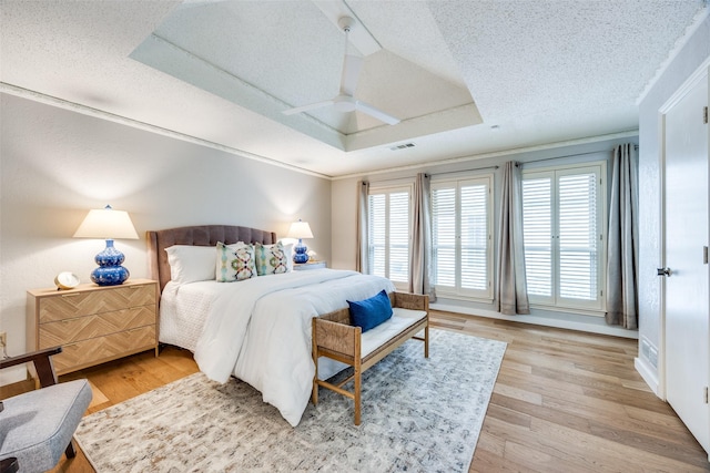 bedroom featuring crown molding, a tray ceiling, wood-type flooring, and a textured ceiling