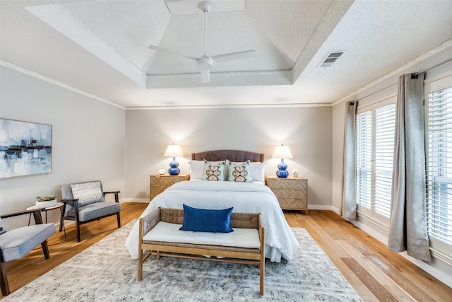 bedroom featuring hardwood / wood-style floors, crown molding, a raised ceiling, and a textured ceiling