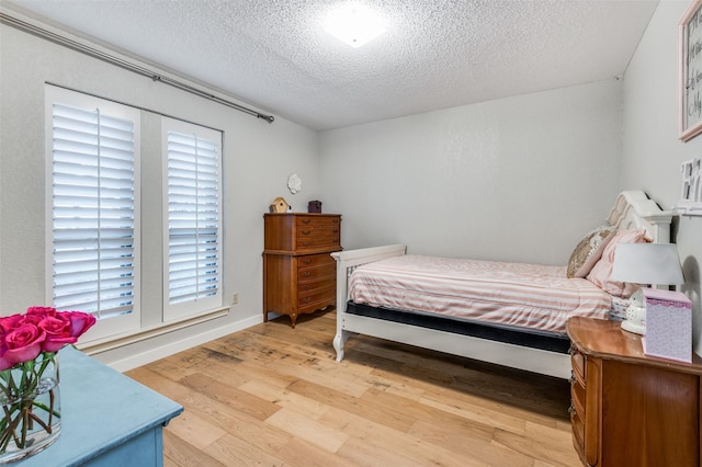 bedroom with a textured ceiling and light wood-type flooring