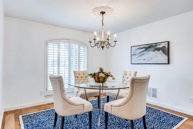 dining area with hardwood / wood-style flooring and a notable chandelier