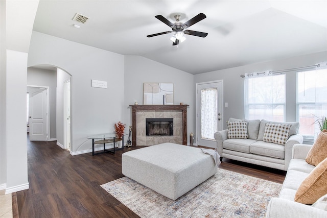 living room with vaulted ceiling, ceiling fan, dark hardwood / wood-style floors, and a tile fireplace