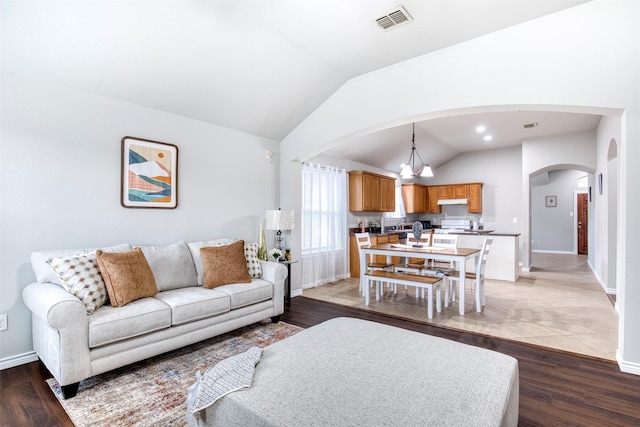 living room featuring lofted ceiling, light wood-type flooring, and a notable chandelier