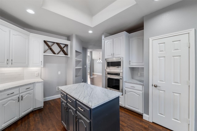 kitchen featuring white cabinetry, light stone countertops, appliances with stainless steel finishes, and a kitchen island