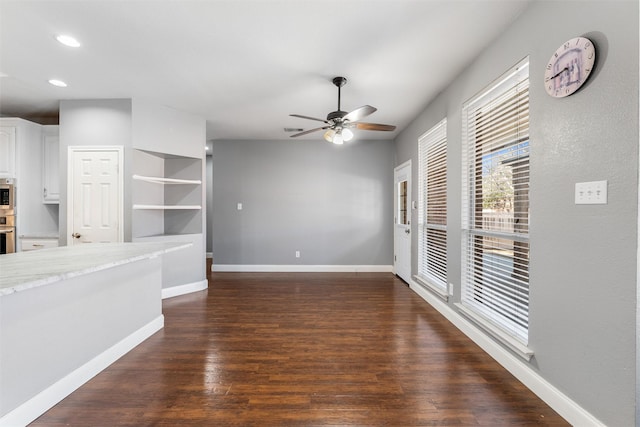 unfurnished living room with dark hardwood / wood-style flooring and ceiling fan