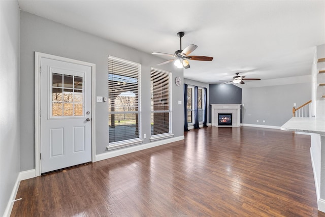 unfurnished living room featuring dark wood-type flooring and ceiling fan