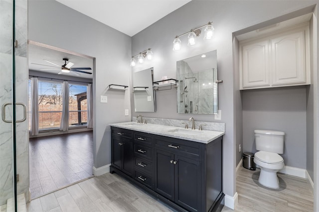 bathroom with hardwood / wood-style floors, vanity, an enclosed shower, ceiling fan, and toilet