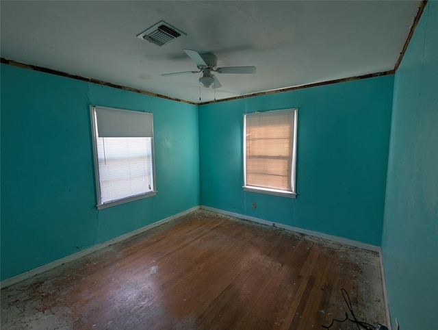 empty room with ceiling fan, wood-type flooring, and plenty of natural light