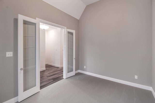 unfurnished bedroom with carpet flooring, a closet, french doors, and vaulted ceiling