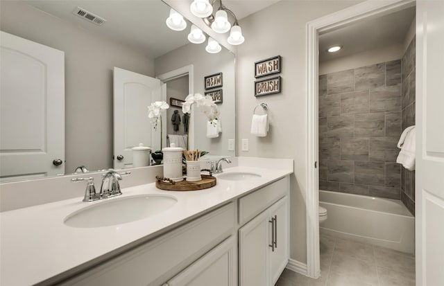 full bathroom featuring toilet, vanity, tile patterned flooring, and tiled shower / bath combo